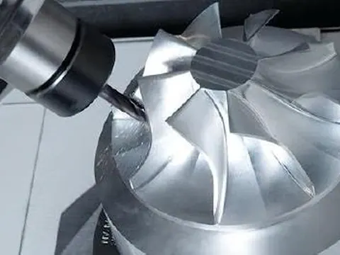 Silver CNC-machined impeller with curved blades and central hub, shown at an angle on a white background