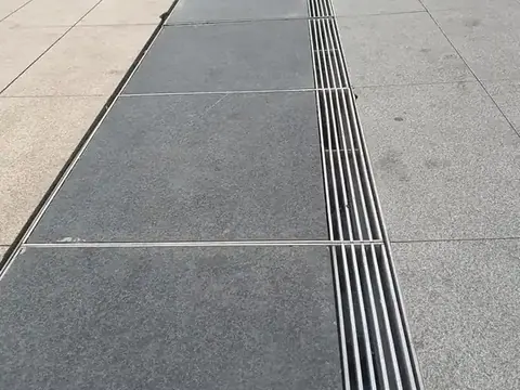 Heel guard grating slots set flush into stone paving outside a building entrance