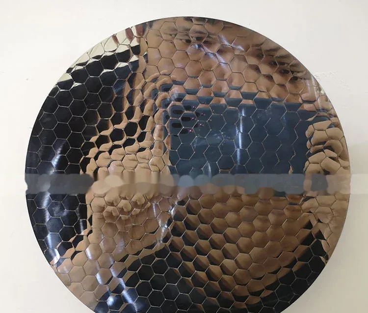 Circular reflective metal disc with a hammered honeycomb texture.