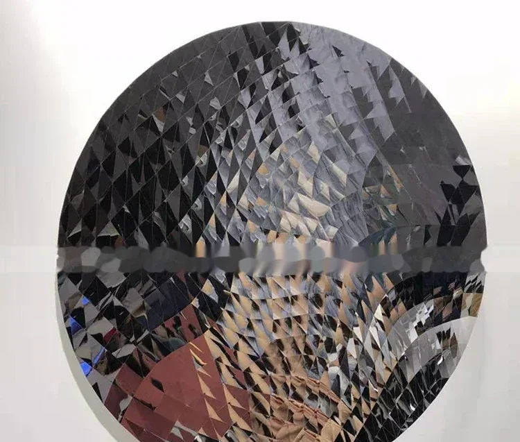 Close-up of a circular etched metal plate featuring a complex geometric triangular pattern.