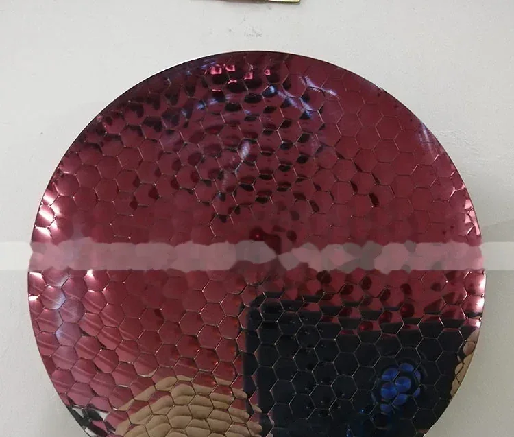 Round red metallic surface with a hexagonal honeycomb texture and a horizontal white line across the middle.