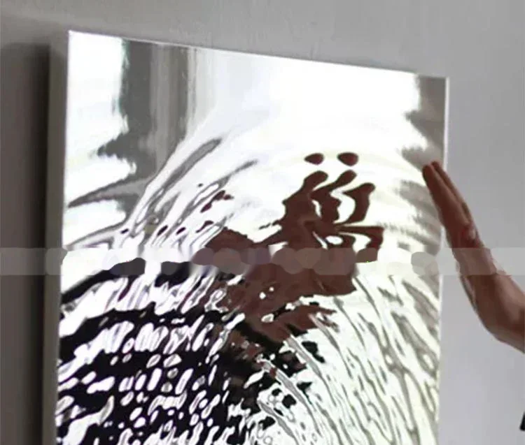 A hand holding a reflective, textured stainless steel panel.