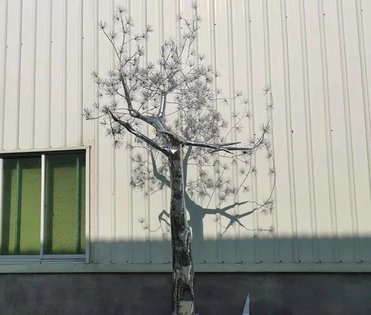 A bare tree stands in front of a corrugated metal building with a window.