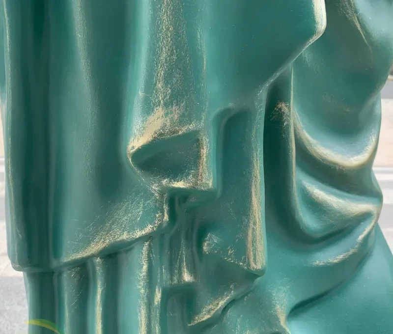 draped, 직물 같은 겹 및 금 악센트를 가진 찻잔 녹색 patinated 조각품의 극단적인 근접