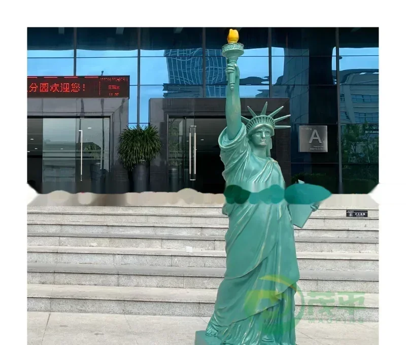 A green statue resembling the Statue of Liberty stands on steps in front of a building with a red sign.