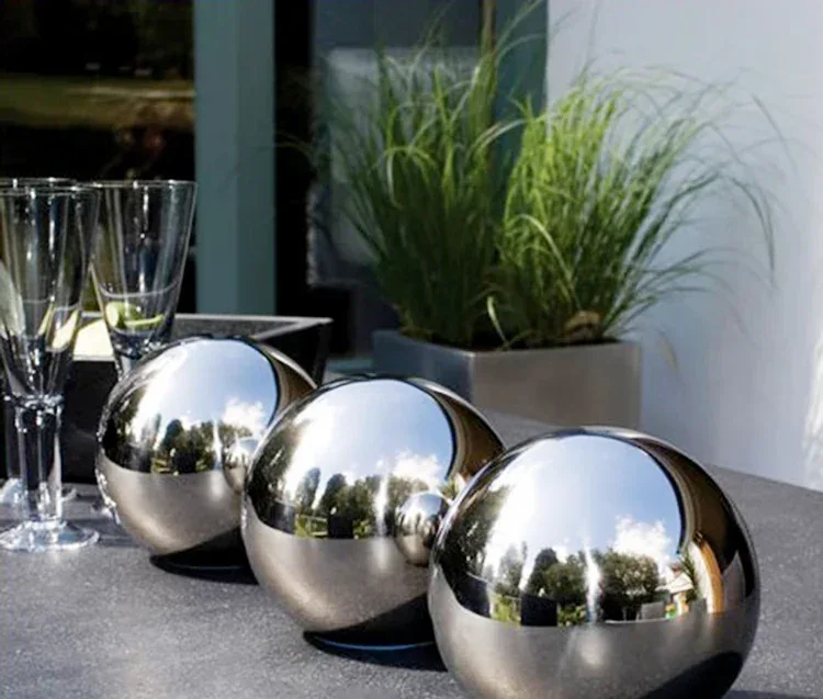 Three polished stainless steel spheres arranged on a table outdoors