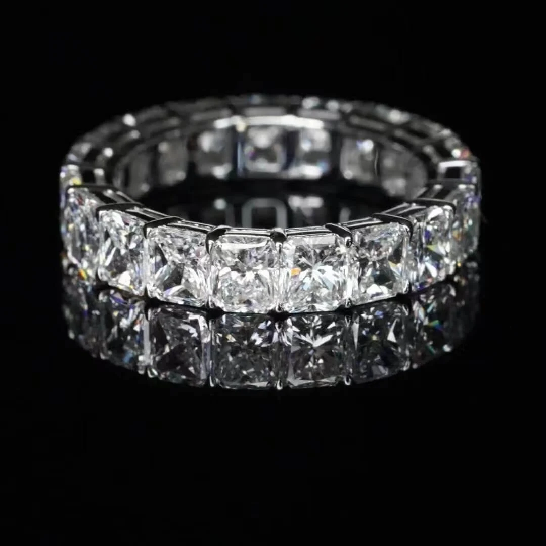 A matched radiant cut diamond eternity band photographed against black