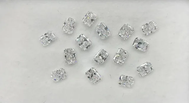 Loose matched radiant cut diamonds laid out on a white ground before setting at BH Jewelry