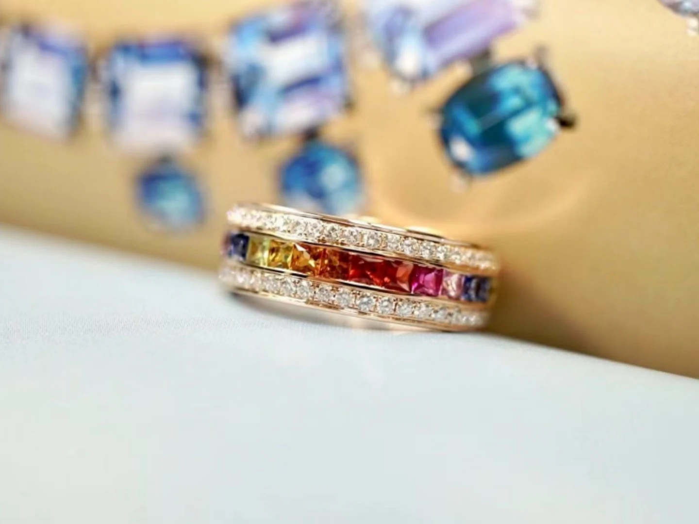 A finished rose gold rainbow sapphire ring held up for inspection at BH Jewelry