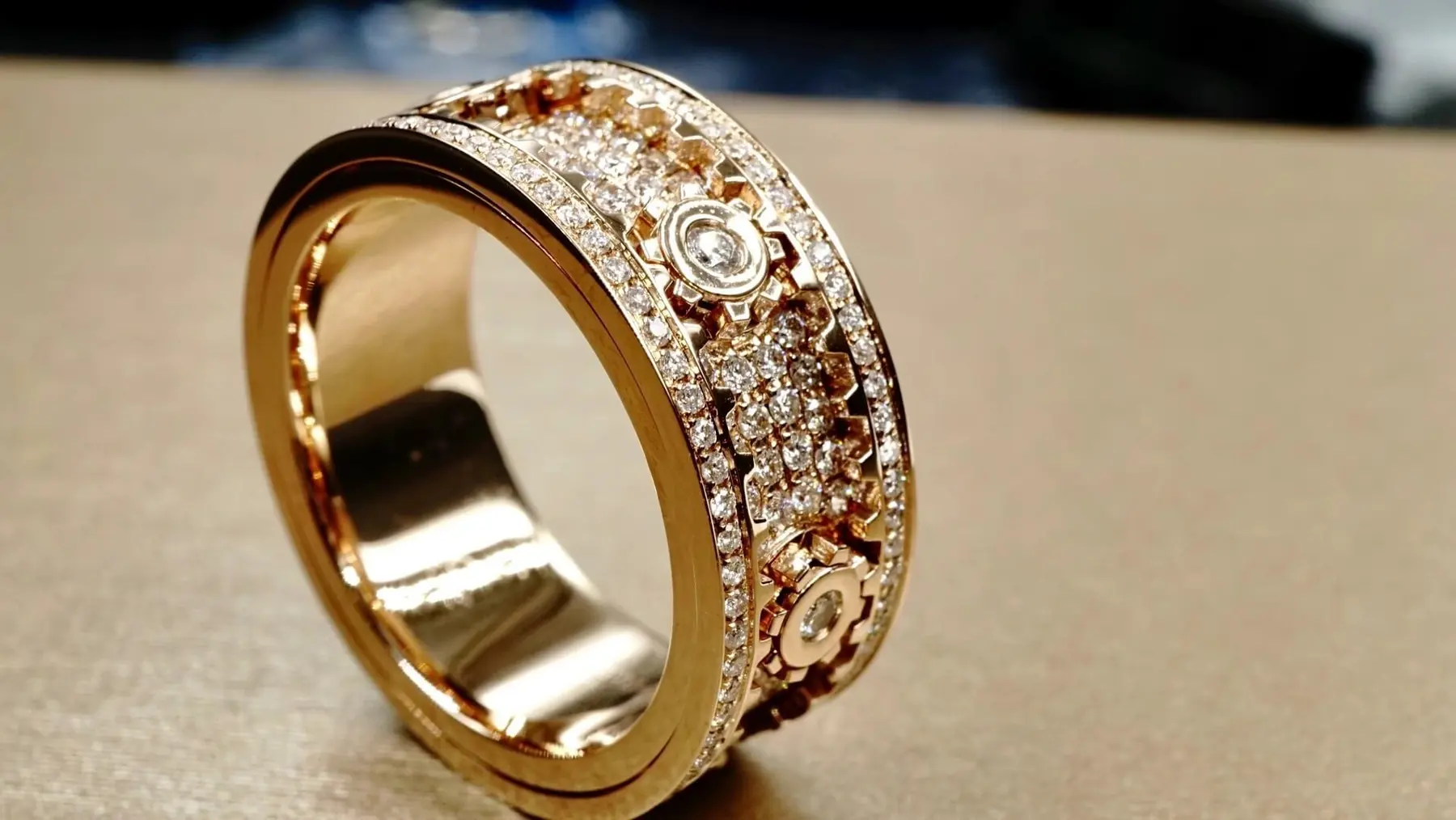 An ornate rose gold geometric band ring with diamond accents photographed in the BH Jewelry workshop