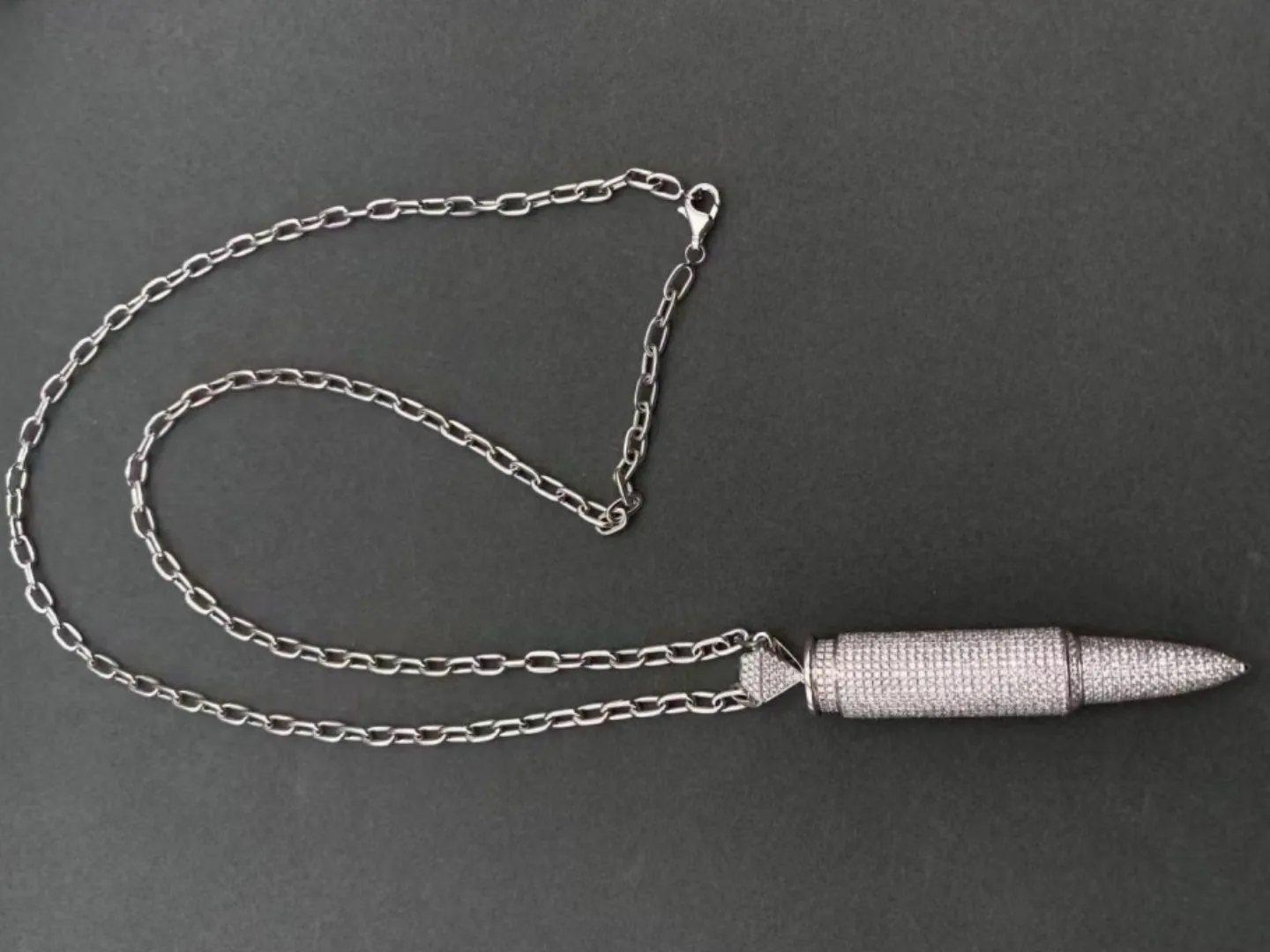 A pave diamond pendant and chain photographed in gloved hands at BH Jewelry