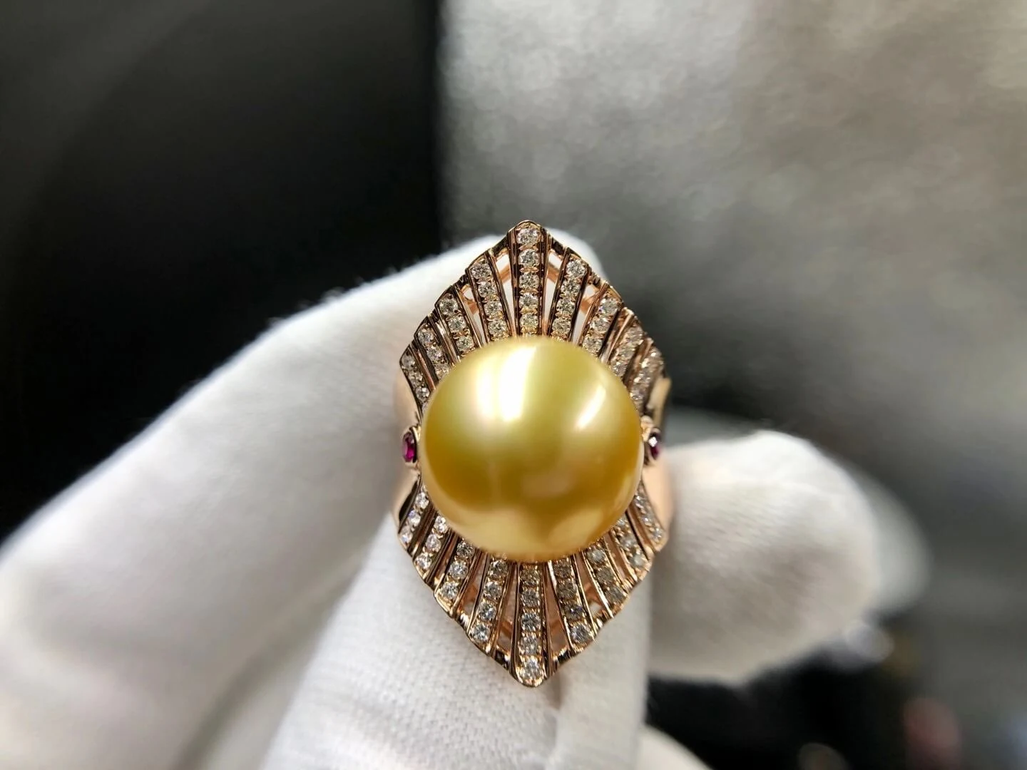 A South Sea golden pearl and diamond ring held in a gloved hand at BH Jewelry