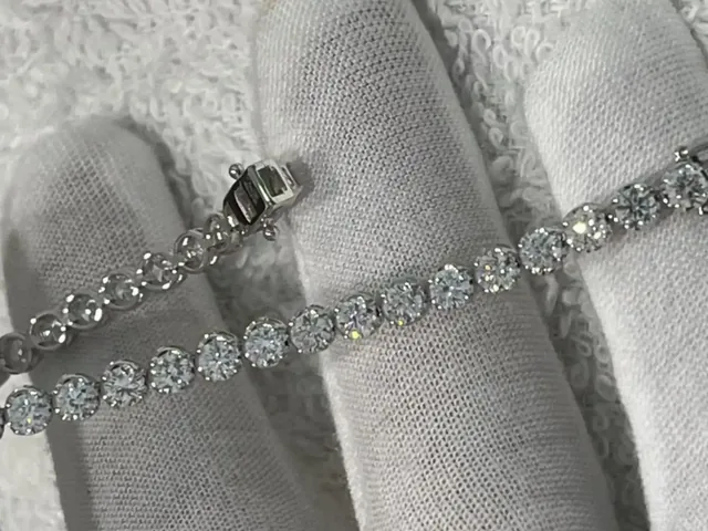 A diamond tennis bracelet inspected in gloved hands at BH Jewelry