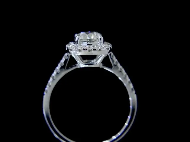 A halo diamond engagement ring photographed on a black ground by BH Jewelry