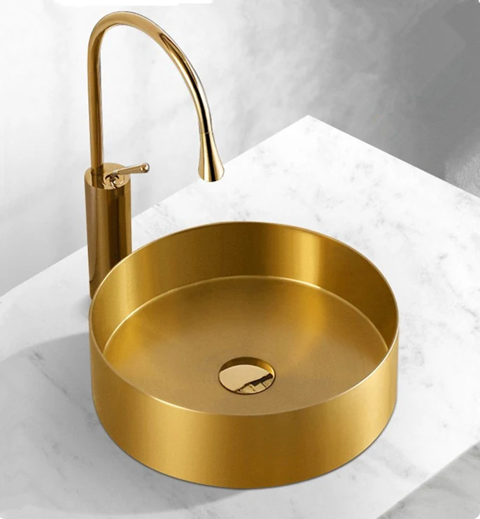 Round gold stainless basin on a marble vanity with a tall gold mixer