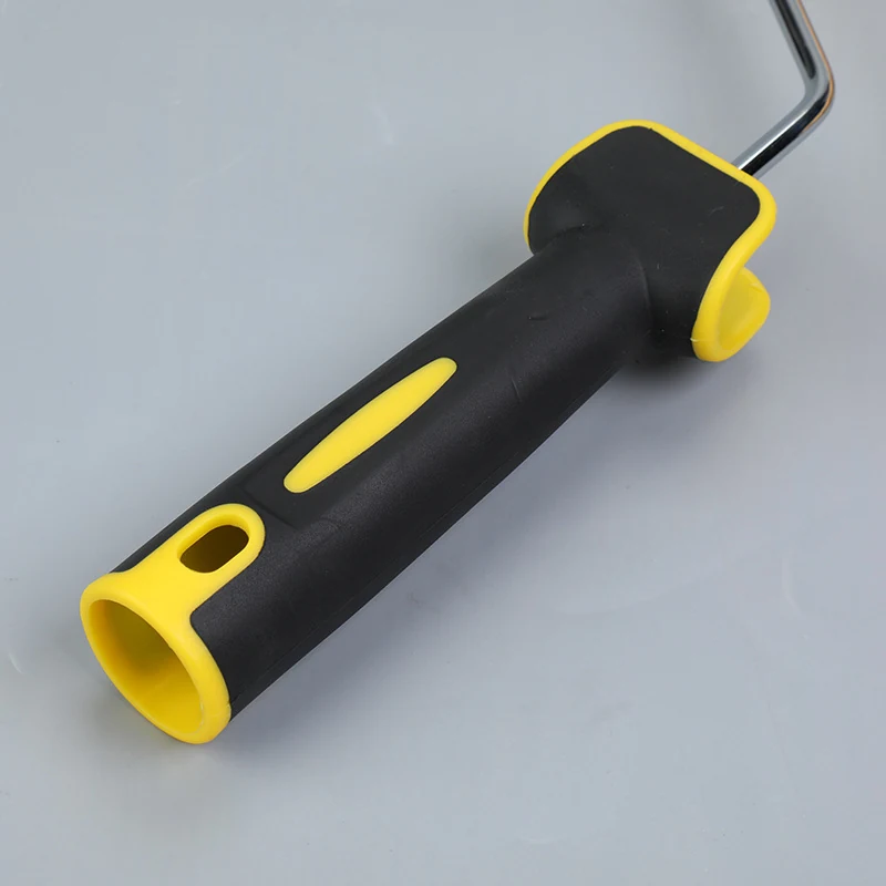 Close-up of a paint roller frame with black rubber grip and yellow accents on a plain gray background