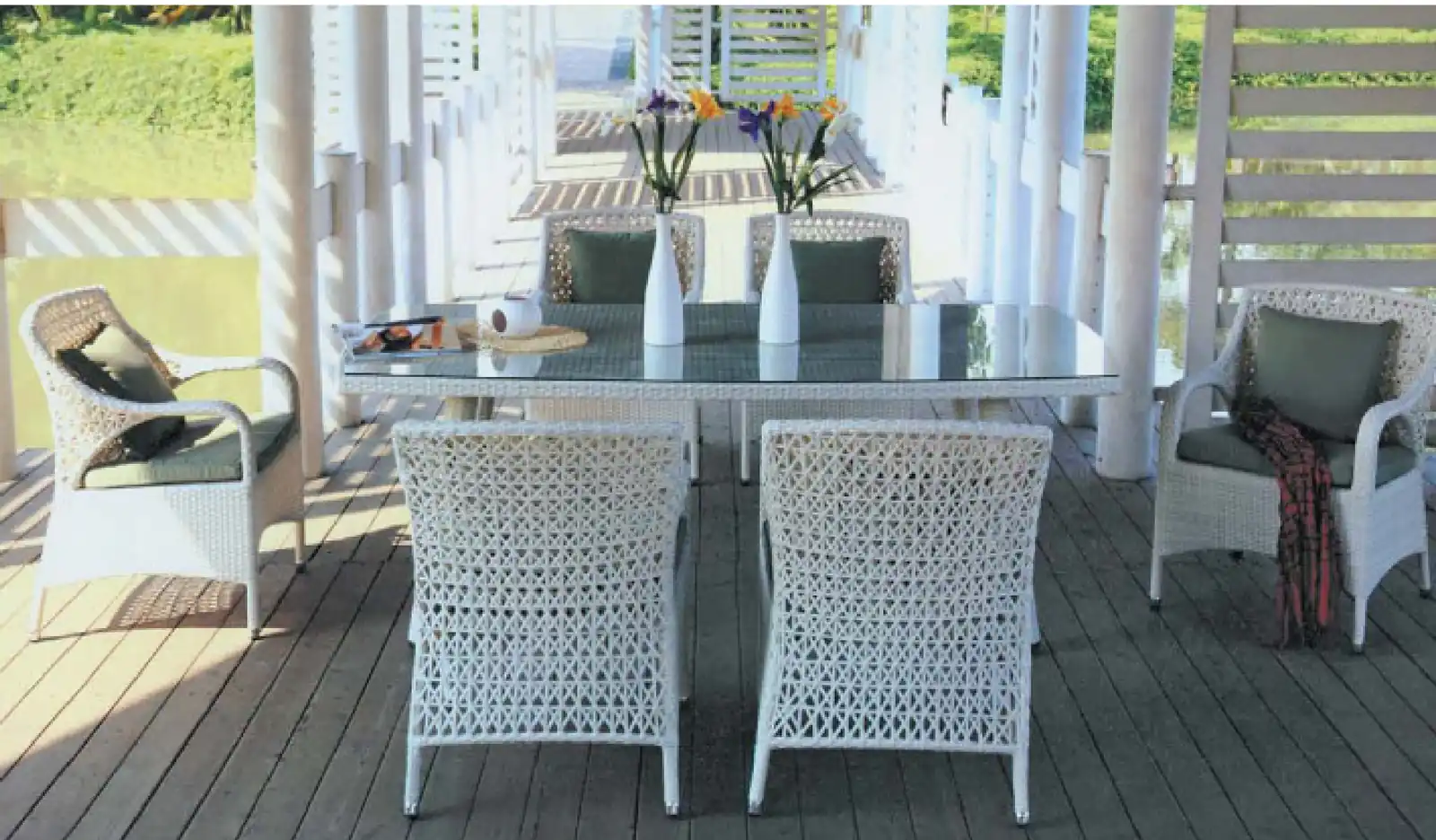 White rattan outdoor dining set with four armchairs on a timber deck