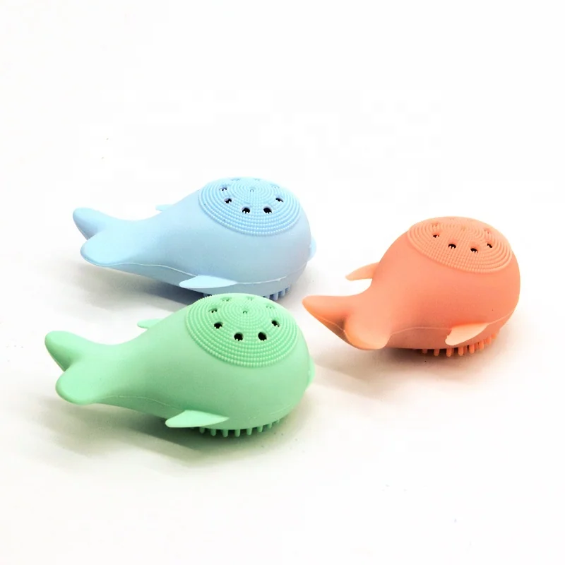 Whale-shaped silicone brush placed on a white surface with a clean towel
