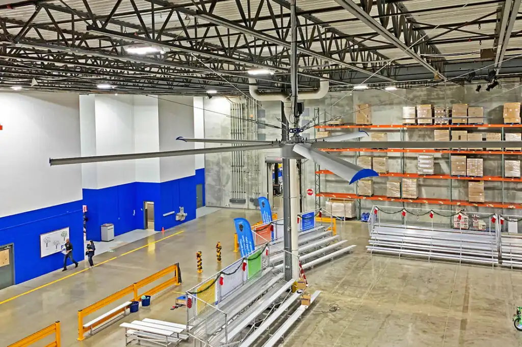 Grandes ventiladores de teto HVLS acima do piso de um armazém usados ​​para destratificação e resfriamento