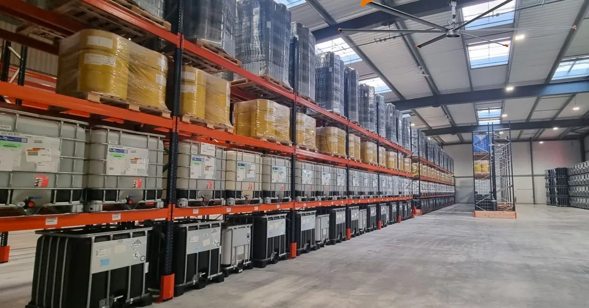 Ventilador de teto HVLS funcionando acima de estantes de paletes em um armazém de produtos químicos
