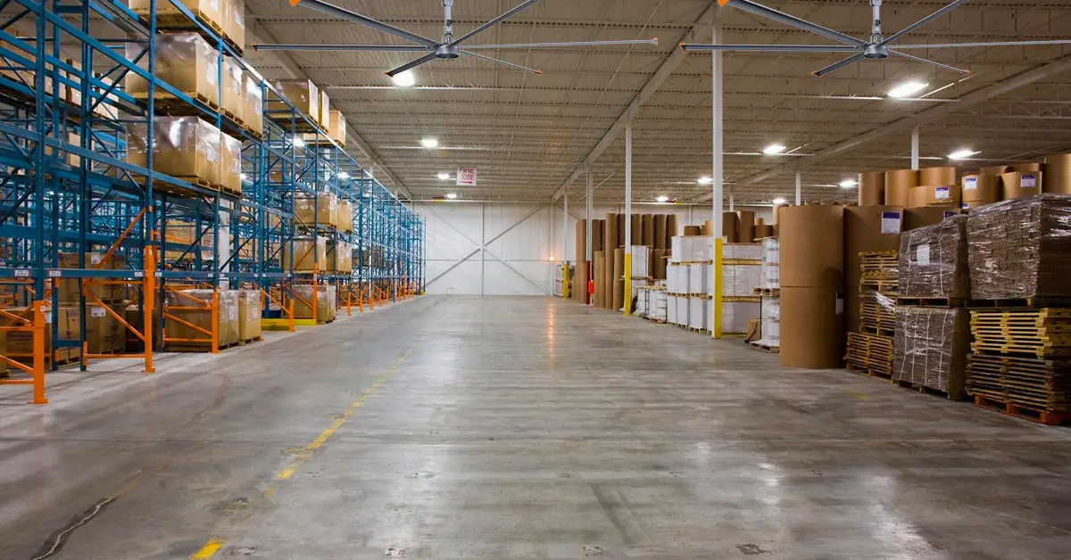 Dois ventiladores de teto HVLS acima do corredor principal de um armazém de distribuição de rolos de papel
