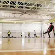 Pavilhão esportivo coberto com ventiladores de teto HVLS acima de uma sessão de futebol infantil