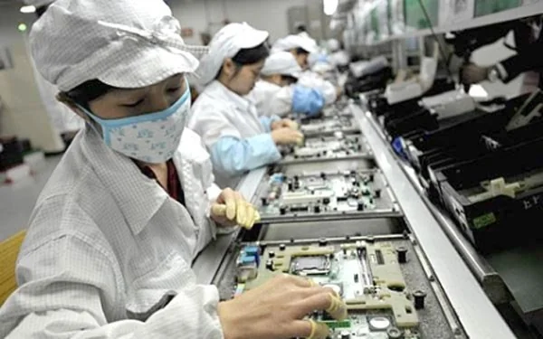 Workers in cleanroom gear assembling electronics on a production line