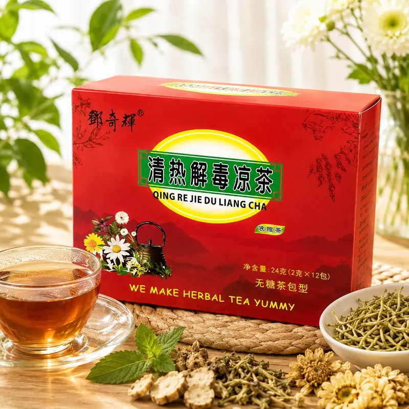 Red box of Chinese herbal tea with English and Chinese packaging text, beside a glass cup of amber tea and dried herbs