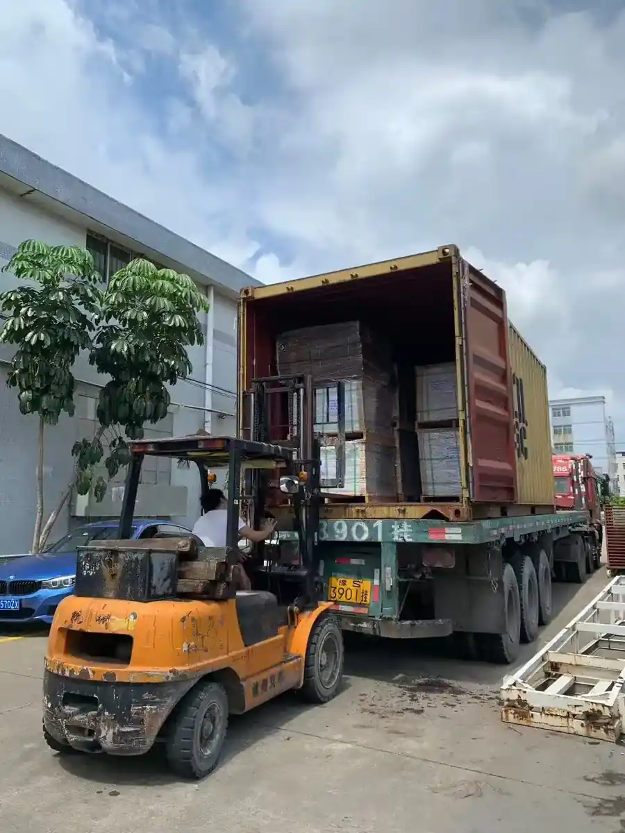 Forklift loading pallets of tile into a shipping container