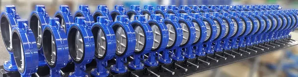 Dual Plate Check Valve Selection Guide: line of assembled blue wafer butterfly valves with hand levers on the packing bench