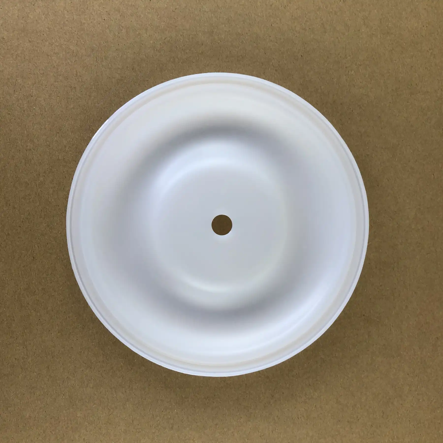 Top-down view of a circular white plastic component with a central hole.