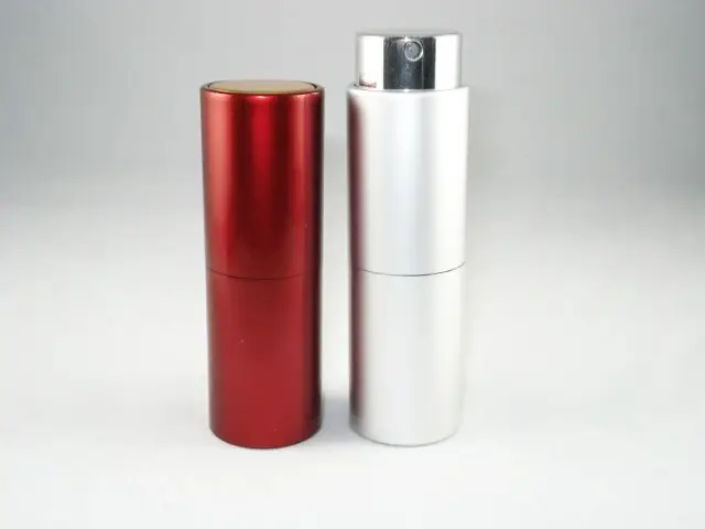 Two cylindrical aluminum spray bottles, one red and one silver, standing on a white backgr