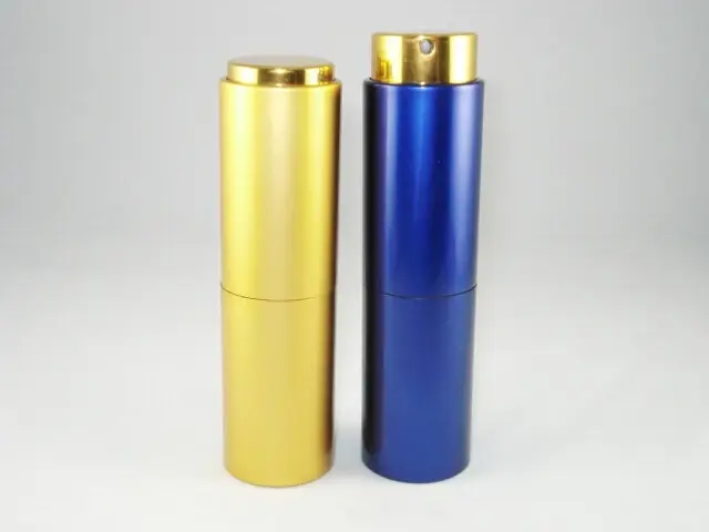 Two aluminum spray bottles, one gold and one blue, with gold pump caps on a light gray bac